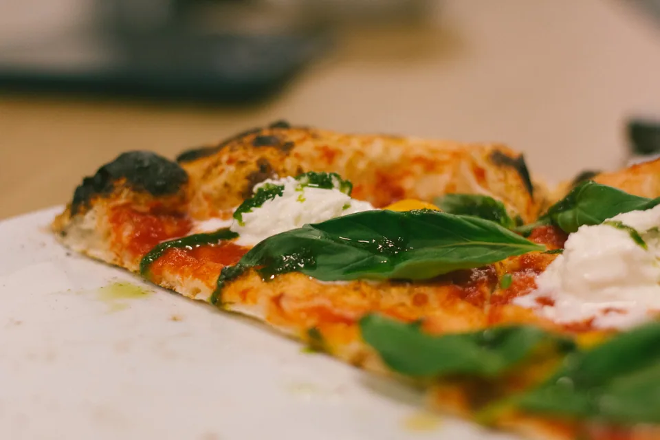 Lähikuva pizzasta, basilikasta ja vaaleasta juustosta